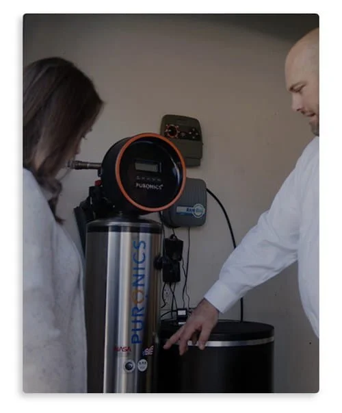 Two individuals examining a silver and black water purification unit