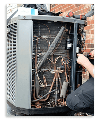 A technician works on an open outdoor air conditioning unit, revealing its internal coils and components